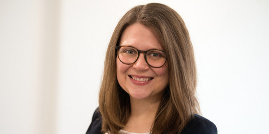 Porträtfoto von Prof. Justine Stang-Rabrig: Prof. Stang-Rabrig trägt einen dunklen Blazer und eine Brille und lächelt in die Kamera.
