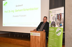 Ein Mann steht an einem Rednerpult. Hinter ihm ist eine Präsentationsfolien an die Wand gebeamt, auf der steht "Grußwort: Prof. Dr.-Ing. Gerhard Schembecker, Prorektor Finanzen".