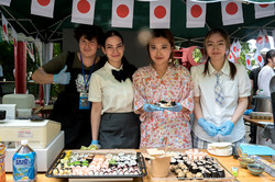 Gruppenfoto von vier Studierenden, die an einem Stand selbstgemachtes Sushi verkaufen.