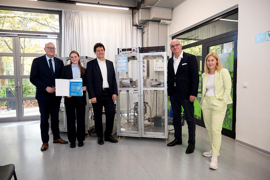 Foto: Fünf Personen posieren für ein Foto neben der Versuchsanlage.