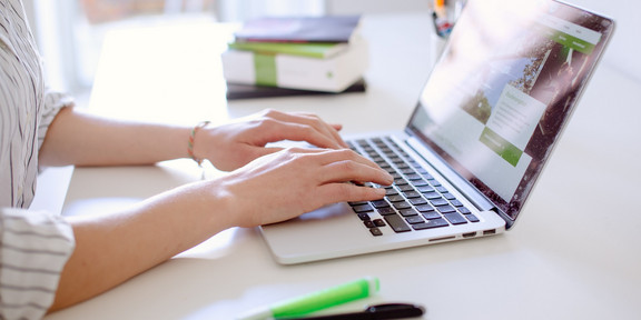 Digitale Lehre Eine Frau sitzt am Laptop an einem Arbeitsplatz und tippt etwas ab.