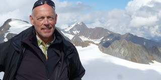 Portrait Klaus Steenweg vor einem verschneiten Bergpanorama 