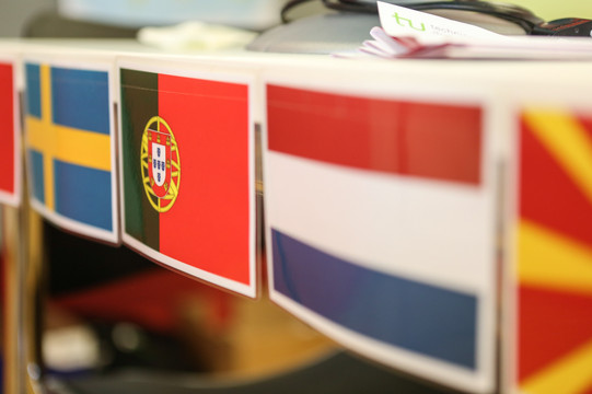 Three small flags next to each other sticking to a shelf.