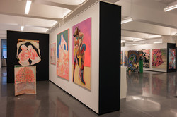 Mehrere Gemälde hängen an den Wänden eines Ausstellungsraumes.