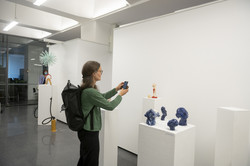 Eine Frau im grünen Pullover fotografiert mit dem Handy ein Kunstobjekt einer Kunstausstellung.