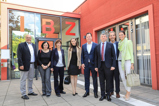 Gruppenfoto von vier Frauen und vier Männern vor einem roten Gebäude, auf dem die Buchstaben IBZ stehen