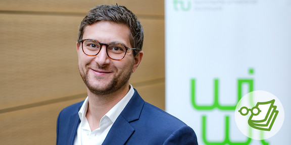 Foto: Eine Person steht vor einer Wand und einem Banner mit dem Logo der TU Dortmund Universität.