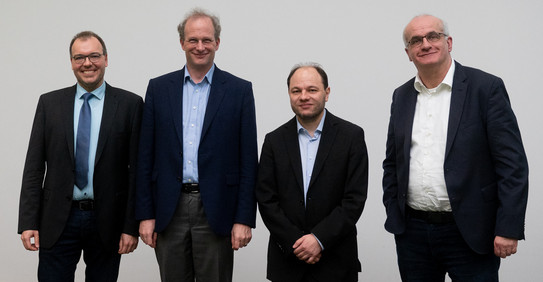 Dr. Jörg Debus, Prof. Georg von Freymann, who gave the keynote speech on THz spectroscopy and quantum sensor technology, Prof. Marc Aßmann and TU Rector Prof. Manfred Bayer in front of a white wall