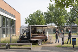 Vier Menschen, die rund um einen mobilen Verkaufswagen für Kaffee stehen