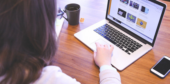 Laptop Eine Frau sitzt vor einem geöffneten Laptop.