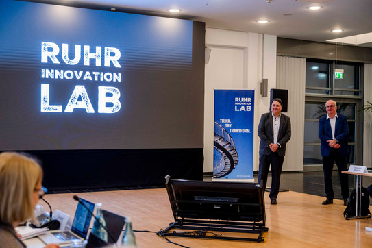 Photo: RUB President Martin Paul and TU President Manfred Bayer stand in front of a display featuring the Ruhr Innovation Lab logo during the dress rehearsal for the inspection.