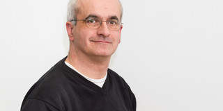 Portraitfoto von Manfred Bayer vor grauem Hintergrund