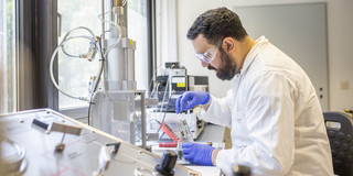 A man in protective clothing carrying out experiments in a laboratory.
