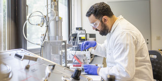 Ein Mann in Schutzkleidung, der in einem Labor Experimente durchführt.