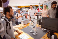 Mehrere Personen stehen um einen Tisch, auf dem ein Fußballroboter steht.