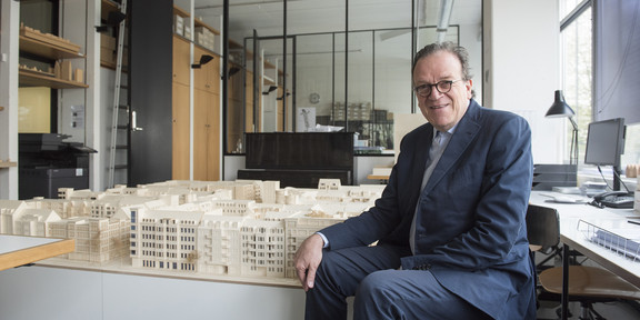 Portrait of Christoph Mäckler next to an architectural model of buildings. 