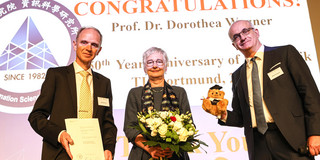 50-jähriges Jubiläum der Fakultät für Informatik Eine Frau und zwei Männer stehen für ein Gruppenfoto auf einer Bühne.