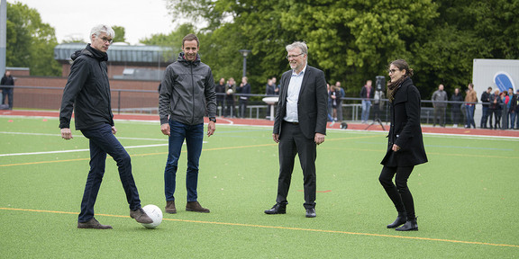 Beschäftigte der TU Dortmund spielen sich auf den Außensportanlagen einen Ball zu.