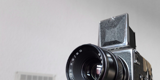 älteres Modell einer Videokamera vor einer Wand mit einem verschwommenen Kalender