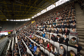 Viele Menschen sitzen auf der Tribüne eines Stadions.