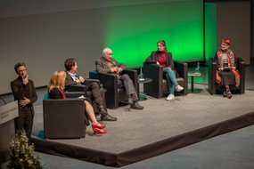 Auf dem Podium im Audimax sitzen die Teilnehmer*innen des Podiumsgesprächs