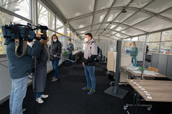 Fernsehreporterin mit Kameramann und Tonmann interviewen einen Studierenden