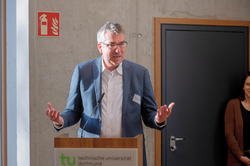 Wulf-Christian Ehrich, ein Mann mit grauen Haaren, Brille und dunkelblauem Anzug, steht an einem Rednerpult und macht beim Sprechen eine Geste Richtung Publikum.