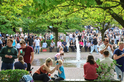 Foto von einem Springbrunnen auf dem Nordcampus der TU Dortmund. Um den Springbrunnen herum sitzen und stehen viele Menschen.