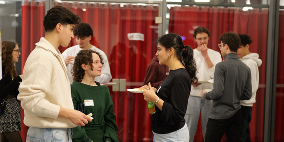 Foto: Einige Personen stehen zusammen und essen Fingerfood.