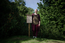 Kunstprojekt Bienenhotels Eine Frau steht neben einen Bienenhotel auf einer Wiese.