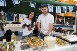 an einem Essensstand lächeln zwei Personen, die Essen zu bereiten, in die Kamera