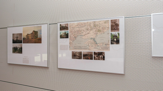 Foto: Mehrere Ausstellungstafeln mit Karten, Fotos und Texten hängen nebeneinander an einer Wand.