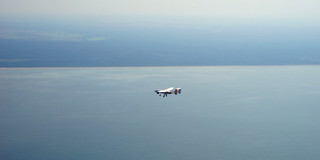 A small plane flies over the sea.