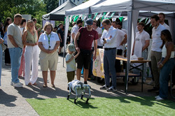 An einem Stand schauen Besucher*innen einem vierbeinigen Roboter zu.