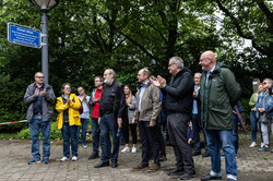 Schild Präsent im Vordergrund wird das neue Straßenschild zur EUnet-Alle gezeigt, dahinter eine große Menge an Gästen
