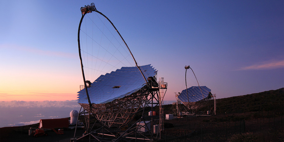 Zwei große Teleskope auf einer Bergkuppe vor einem Abendhimmel.
