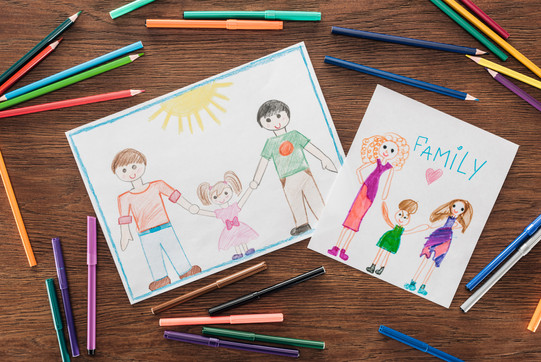 Das Foto zeigt zwei von Kindern gemalte Bilder, die Familien mit gleichgeschechtlichen Eltern zeigen