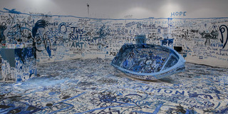 Ein großer Raum mit blau bemalten und beschriebenen Wänden und Böden und einem blauen Boot in der Mitte.