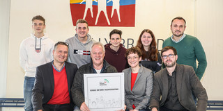 Ein Gruppenbild mit Jugendlichen und Erwachsenen, die ein Schild mit der Aufschrift Schule im NRW-Talentscouting halten.