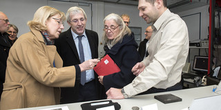 Ein Ingenieur beschreibt der Ministerin, dem Staatssekretär und der Rektorin Bauteile.
