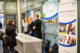 Drei Frauen stehen hinter und zwei Frauen stehen vor einem Informationsstand.