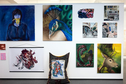 Eine Wand in der Ausstellung, die verschiedene Kunstwerke in unterschiedlichen Größen zeigt