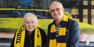 Zwei Männer mit BVB-Schals halten eine Urkunde in den Händen.