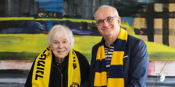 Zwei Männer mit BVB-Schals halten eine Urkunde in den Händen.