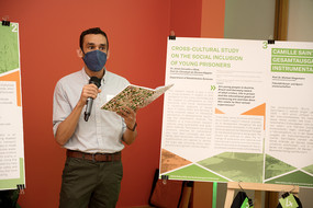 A man stands next to a poster and speaks into the microphone