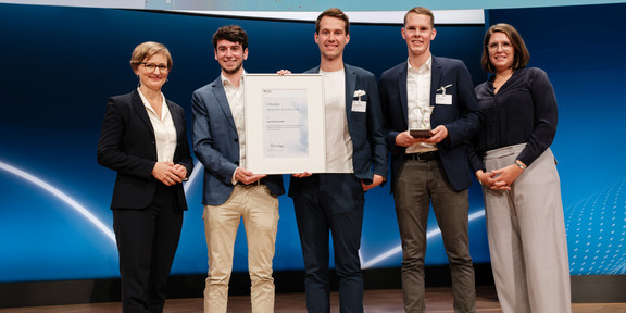 Das Bild zeigt Franziska Brantner (Parlamentarische Staatssekretärin beim Bundesminister für Wirtschaft und Klimaschutz), wie sie die Auszeichnung als „Digitales Start-up des Jahres“ an Patrick Elfert, Dr. Philipp Hüning und Felix Lütjann von der Logistikbude übergibt.