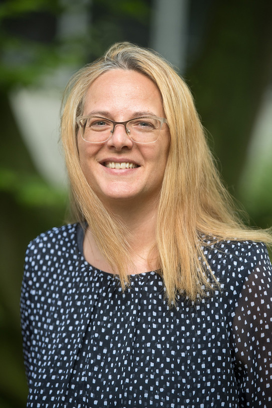 Ein Portrait einer Frau mit Brille und blonden Haaren.