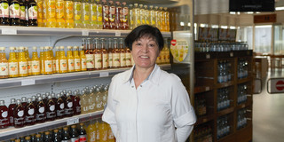 Portrait von Antoinette Lonzynski vor einem mit Getränkeflaschen gefüllten Kühlregal