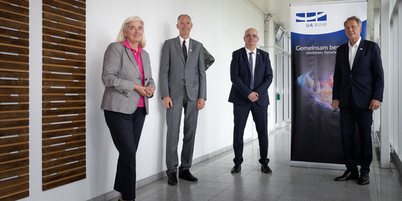 Research Alliance Ruhr Eine Frau und drei MäA woman and three men are standing in a hallway.nner stehen in einem Flur.