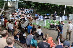 Foto: Bei einem Spiel der Fußballroboter sitzen Personen auf Rängen im Publikum.